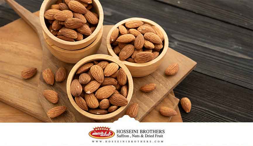 چند ظرف حاوی بادام بر روی یک تخته چوبی